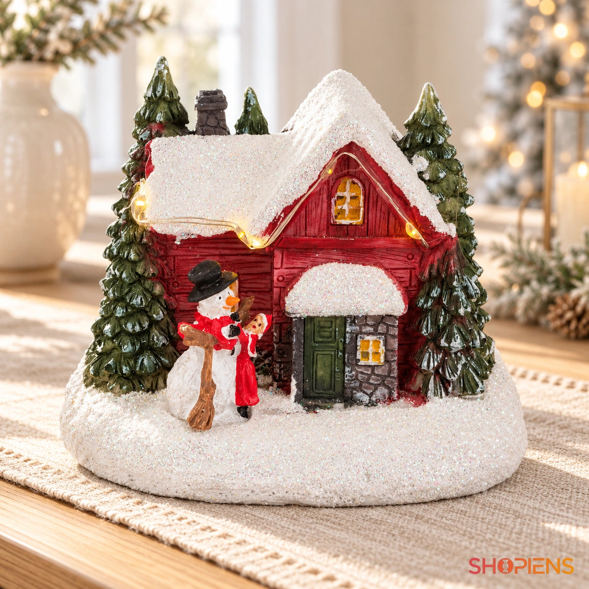 Căsuță ninsă cu om de zăpadă și LED, 11 × 9 × 10 cm pe o consolă, într-un decor festiv în lumină naturală | Shopiens®