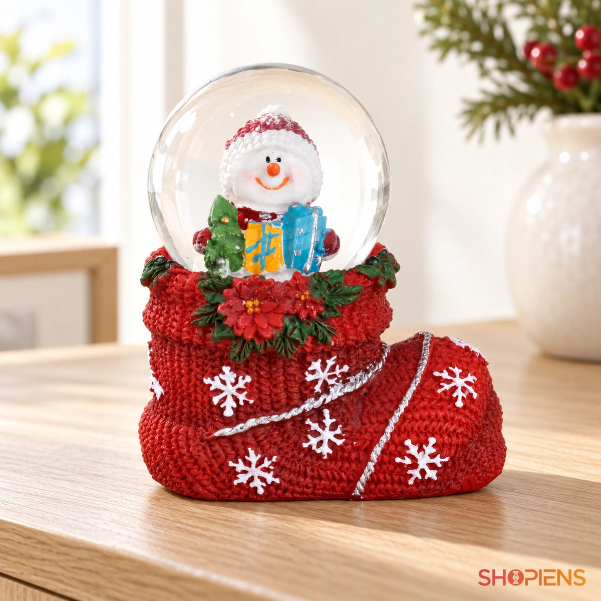 Glob cu om de zăpadă în cizmă roșie pe o consolă într-un decor luminos | Shopiens®