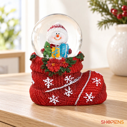 Glob cu om de zăpadă în cizmă roșie pe o consolă într-un decor luminos | Shopiens®