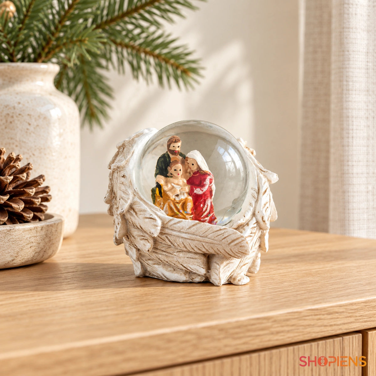 Glob cu sfânta familie și aripi de înger, 6 cm pe o consolă într-un decor luminos | Shopiens®