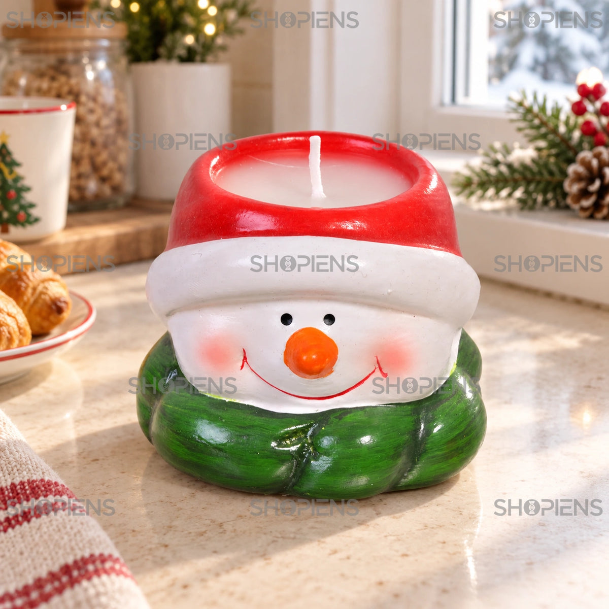 Lumânare om de zăpadă cu căciulă roșie, 6 cm, lângă o fereastră într-un decor de iarnă | Shopiens®