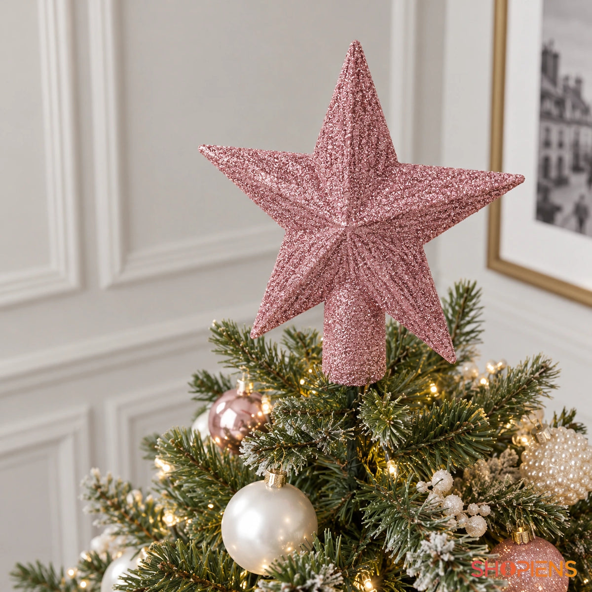Stea roz cu glitter pentru vârful bradului, 15 cm în vârful bradului, fotografiată de sus lângă un perete cu profile decorative | Shopiens®